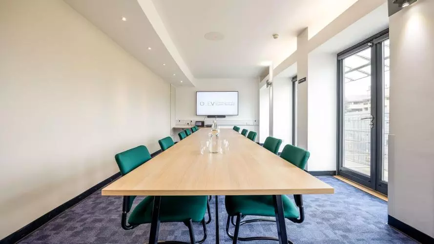 Meeting Room 01 laid out in boardroom style looking towards the screen